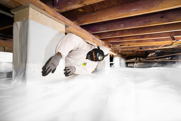 Technician installing insulation and a moisture barrier in a residential crawlspace